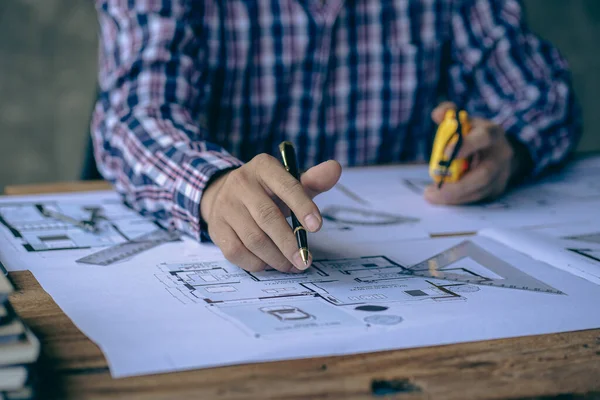 Close-up of a man working on a project sketching architects on blueprints at a construction site. Architect, engineer concept in desk construction project bannerclose-up of drawing plans with architect equipment