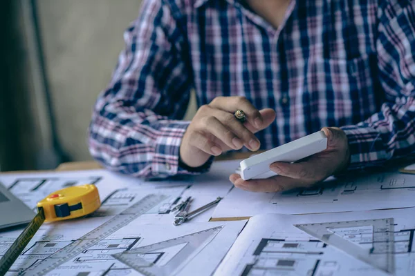 Close-up of a man working on a project sketching architects on blueprints at a construction site. Architect, engineer concept in desk construction project bannerclose-up of drawing plans with architect equipment