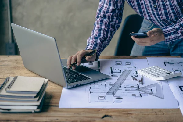 Close-up of a man working on a project sketching architects on blueprints at a construction site. Architect, engineer concept in desk construction project bannerclose-up of drawing plans with architect equipment
