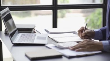a business man looking at a financial chart on a notebook cheerful man analyzingwork in the office Gadgets and documents with graphs and data. 4k video.