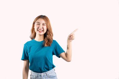 Zarif bir Asyalı kadın mutlu bir şekilde gülümser ve beyaz arka planda ayrı bir boşluğa işaret eder..