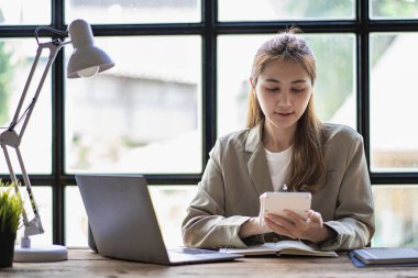 Güzel hırslı Asyalı kadın çalışan evden çalışıyor. Dizüstü bilgisayar kullanan kız rüya gibi gülümsüyor. Öğrenciler kompozisyon yazmak için ilham alıyorlar..