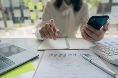 A businessman holding a smartphone working on project statistics on the device is ready. Graph presentation, notebook, entrepreneur, financial market data analysis. that represents a change