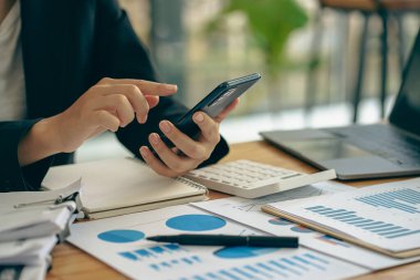 A businessman holding a smartphone working on project statistics on the device is ready. Graph presentation, notebook, entrepreneur, financial market data analysis. that represents a change