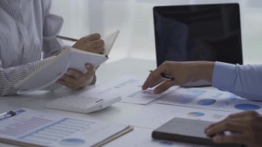 İş ekibi verileri analiz eden bir dizüstü bilgisayardaki toplantı grafiğinde iş verilerinin istatistiksel analizi. İki iş arkadaşı, çözüm sunmak için beyin fırtınası yapan belgeler ve grafikler üzerinde çok çalışıyor. 4k video