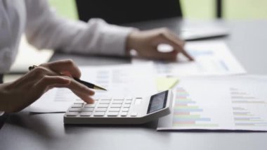 business man calculating write on notebook with pen and type the data into the laptop financial analysis