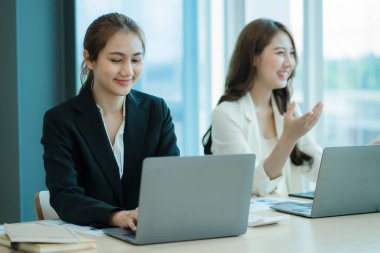 Masada dizüstü bilgisayarları ve finansal belgeleri olan iki Asyalı kadın muhasebeci var..
