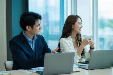 Finansal Grafik bilgisayar ofisinde birlikte çalışan iki genç Asyalı iş adamı. Fikirlerinizi paylaşın, iş planlarınızı tartışın ve eğitin..