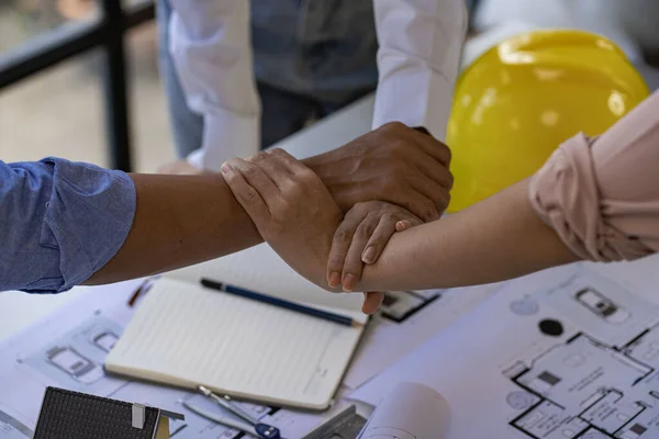 Architect engineers shake hands with hats and houses on construction tool tables. with blueprints on the table - business teamwork working together Successful Collaboration Ideas