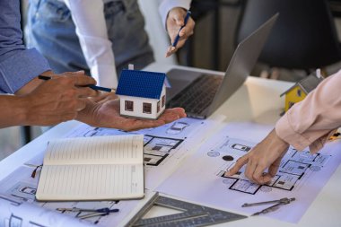 Engineer and architect team meeting with helmet and house on construction tool table With blueprints on the table - successful business collaboration. successful cooperation concept