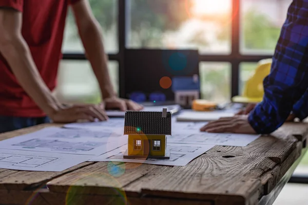 Engineer and architect team meeting with helmet and house on construction tool table With blueprints on the table - successful business collaboration. successful cooperation concept