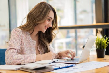 Beautiful Asian businesswoman, professional millennial woman or female financial analyst working on financial graphs and chart data in the office.