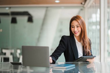 beautiful asian business woman Millennial professional female financial analyst working on financial charts and chart data with laptop in the office.