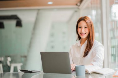 Professional and intelligent Asian businesswoman or female financial analyst working on her financial reports. Analyze graphs and charts with a laptop.