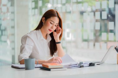 Professional and intelligent Asian businesswoman or female financial analyst working on her financial reports. Analyze graphs and charts with a laptop.