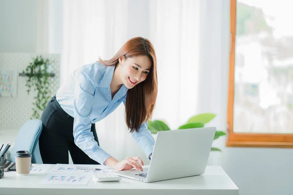 beautiful asian business woman Millennial professional female financial analyst working on financial charts and chart data with laptop in the office.