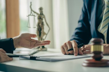 Businessmen and lawyers discuss contract documents with brass scales and judges' hammers on wooden tables in the office. Legal services. Advice. Justice concept.
