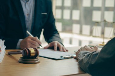 Businessmen and lawyers discuss contract documents with brass scales and judges' hammers on wooden tables in the office. Legal services. Advice. Justice concept.