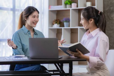 Starting a business, two young Asian women discuss working on investment projects and planning strategies. Businessman talking with laptop computer at office