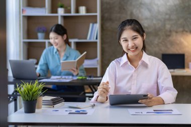 Starting a business, two young Asian women discuss working on investment projects and planning strategies. Businessman talking with laptop computer at office
