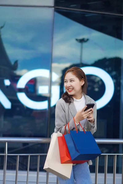 Smiling Asian Woman Colored Shopping Bags Shopping Mall Background Looking — Φωτογραφία Αρχείου