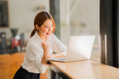 Happy Asian female student wearing headphones, studying online, watching webinars, podcasts on tablets, listening, learning, education courses. online meeting