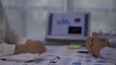 Young businessmen shaking hands in the office Complete a successful meeting with financial graphs and a laptop on a 4k table.