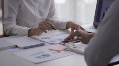 Two young businessmen in a graph pointing to a meeting in a laptop analyzing data. Old man CEO talking to customers in office 4k
