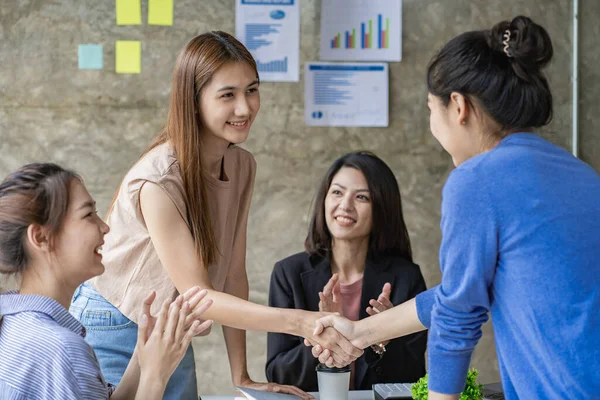 Women in business partners in Asia shake hands during a meeting in a modern office. A beautiful colleague smiles in a friendly way and shakes hands after the deal is made and the friends applaud.