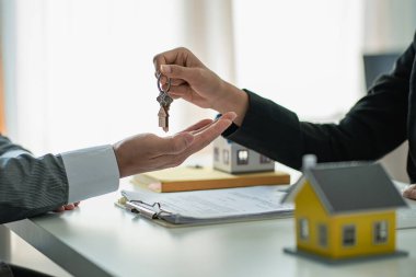 Real estate agents provide keys to customers after signing a contract, renting or buying a home with home loan and home insurance offers.