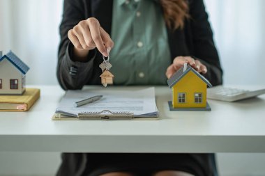 Real estate agents provide keys to customers after signing a contract, renting or buying a home with home loan and home insurance offers.