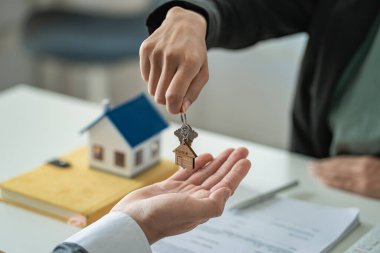 Real estate agents provide keys to customers after signing a contract, renting or buying a home with home loan and home insurance offers.