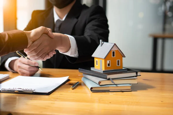Real estate agents shake hands with customers after signing contracts. Rent or buy a home with home loan and home insurance offers.