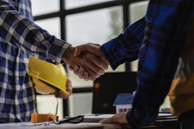 Engineers and construction supervisors shake hands after a consultation meeting to begin planning a new contract in the construction site office. team work concept working together and contractor