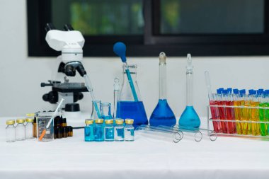 Chemistry Research Laboratory Bottles containing colored liquids and a microscope with a rod molecular model and a pipette add the sample to the test tube.
