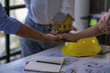 A team of engineers and architects holding house designs in their hands. Contractors and technicians are having a brainstorming meeting for a project together. successful.