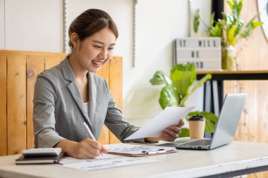Professional Asian female accountant or financial clerk at her job who works on financial reports. and laptop computers and