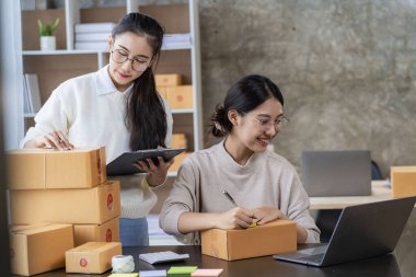 Two independent Asian women working from home small business owners inspect products before delivering them to customers online. shipping packaging Online marketing for SMEs, startups, concepts