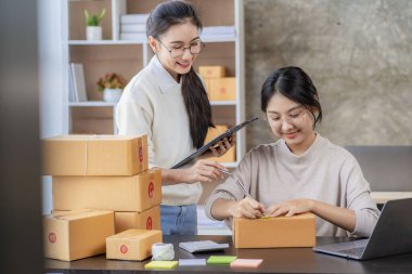 Two independent Asian women working from home small business owners inspect products before delivering them to customers online. shipping packaging Online marketing for SMEs, startups, concepts