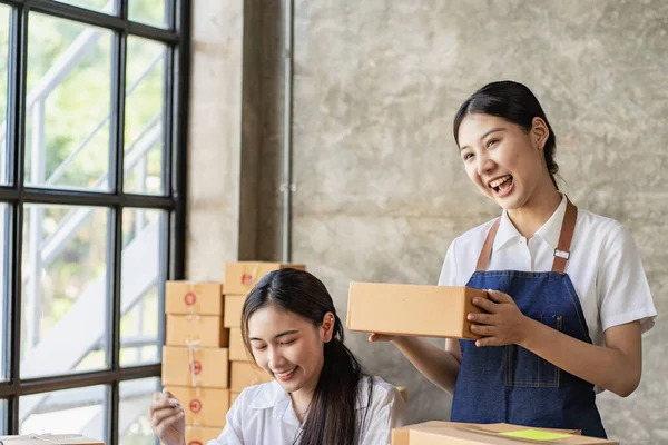 Two independent Asian women working from home small business owners inspect products before delivering them to customers online. shipping packaging Online marketing for SMEs, startups, concepts