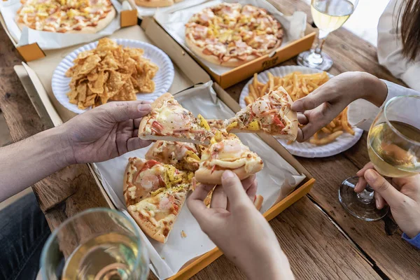 Group of male and female colleagues having pizza lunch together at the office after work celebration concept