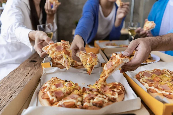 Group of male and female colleagues having pizza lunch together at the office after work celebration concept