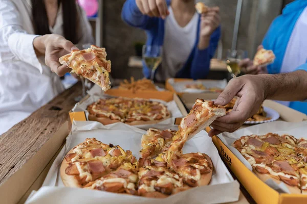 Group of male and female colleagues having pizza lunch together at the office after work celebration concept