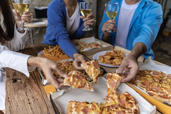 Group of male and female colleagues having pizza lunch together at the office after work celebration concept