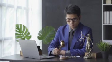 Asian middle aged male lawyer working on laptop and legal contract documents in courtroom Hammer and Goddess Scales concept of consulting and legal services 4k