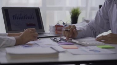Two Asian businessmen and businesswomen analyze data on graphs of rising finances, sales, revenues and profits during meetings in a conference room at a modern office. 4k