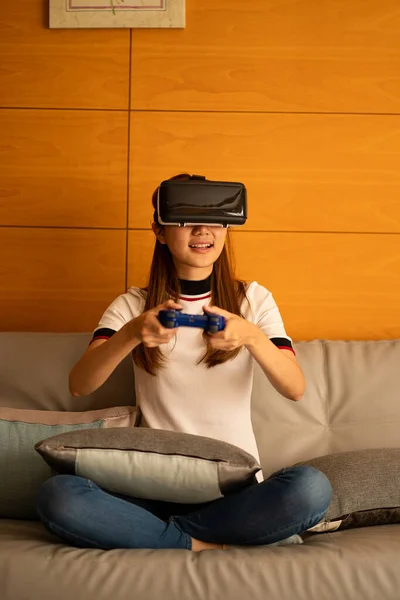 girl sitting on the sofa wearing virtual reality glasses Look at the website online and use the hand-animated 3D simulated screen, future technology concept.