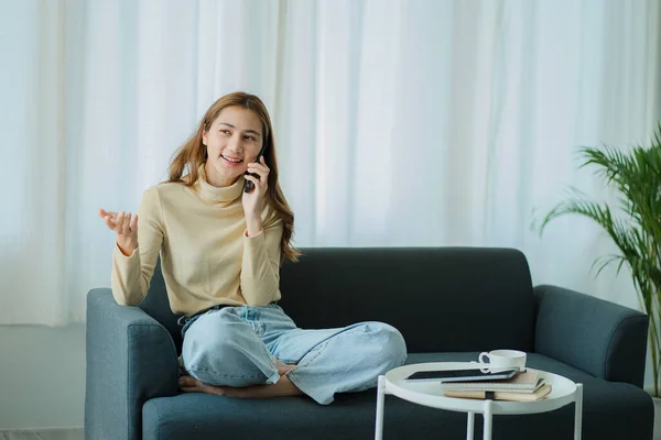 Asian girl talking phone on sofa at home