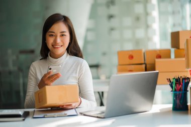 Small business startups, SME owners, Asian women entrepreneurs Successfully working with boxes and checking online orders with a laptop to prepare. Sell to customers. Online SME Business Ideas