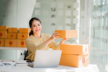 Small business startups, SME owners, Asian women entrepreneurs Successfully working with boxes and checking online orders with a laptop to prepare. Sell to customers. Online SME Business Ideas